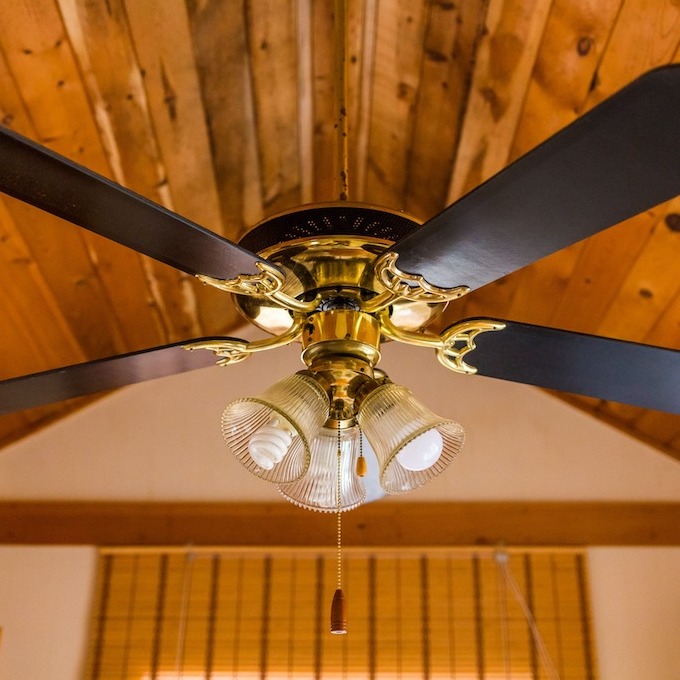 A brand-new ceiling fan installation with a wooden ceiling in the background