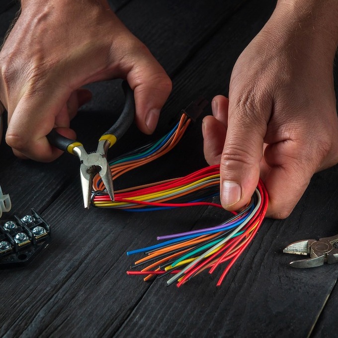 electrical services as depicted by an electrician with pliers and multi-colored wires