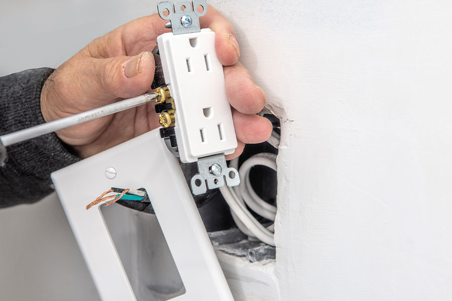 Electrician performing electrical outlet installation